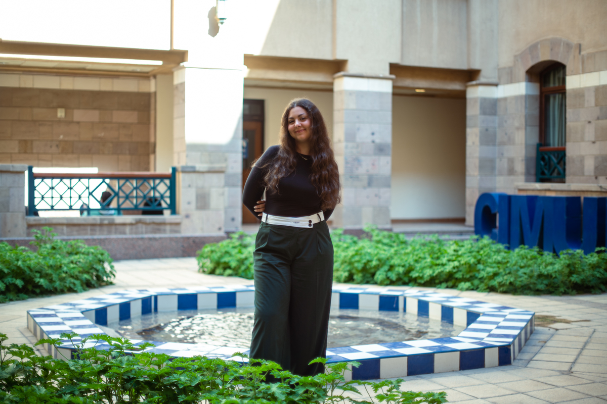 woman stands in front of a fountain inside a courtyard at AUC