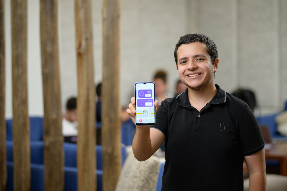 Man standing holding up his phone with an application open on it